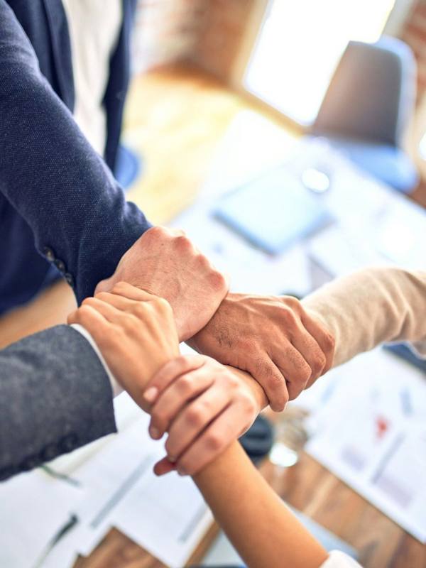 Team members joining hands over a work table